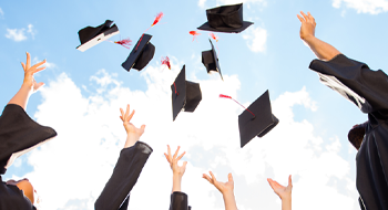 people throwing graduation hats
